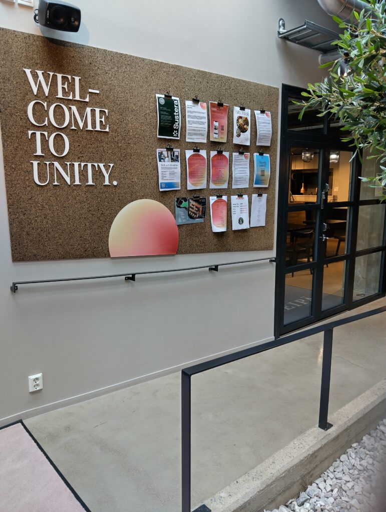 Sisätilassa ilmoitustaulu, jossa lukee "Wolcome to Unity"