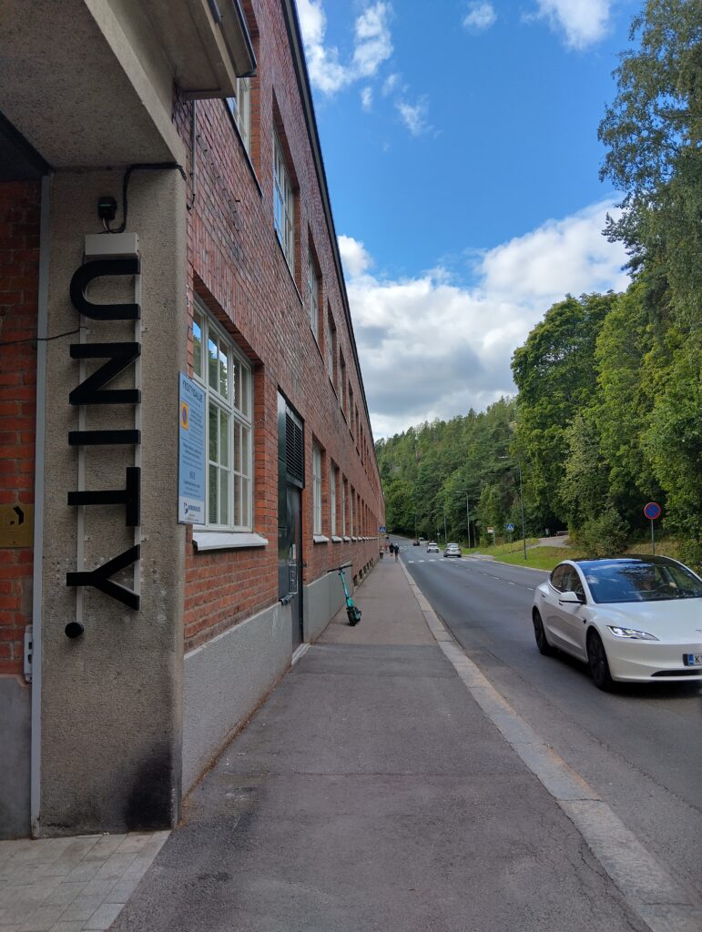 Tiilirakennuksen edusta. Seinässä lukee "UNITY".